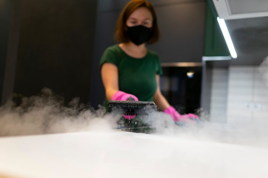 Woman employee cleaning company blows vapor out of steam generator.